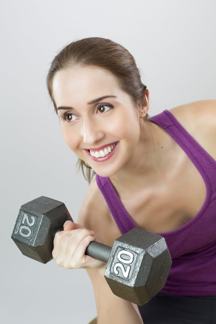 gallery-6 Young woman exercises with 20 lb dumbbell, showing strength and positivity.