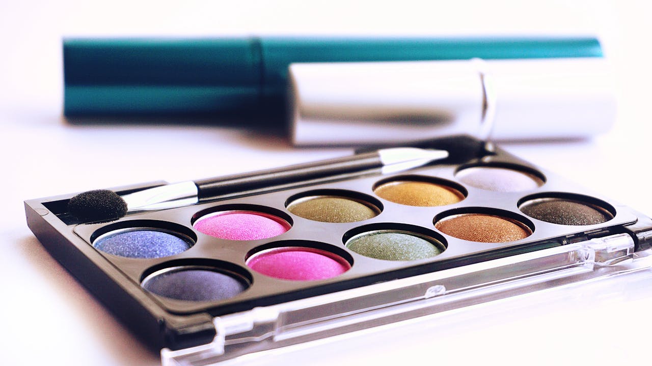 our-services-1 Close-up of colorful eyeshadow palette with brush, ideal for fashion and beauty themes.