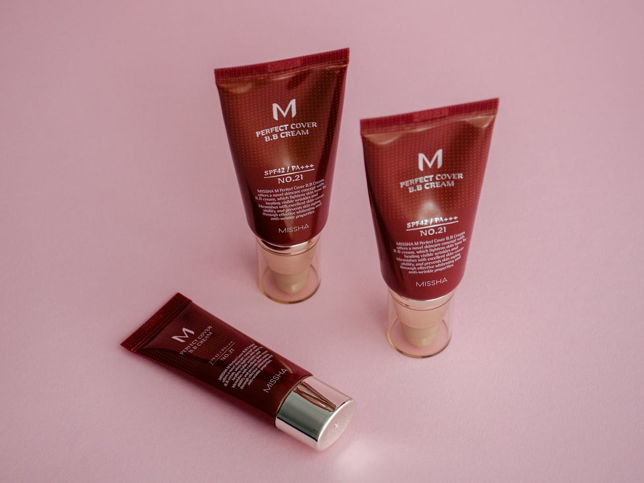 about-01 BB cream tubes on a vibrant pink background showcasing skincare and cosmetics.