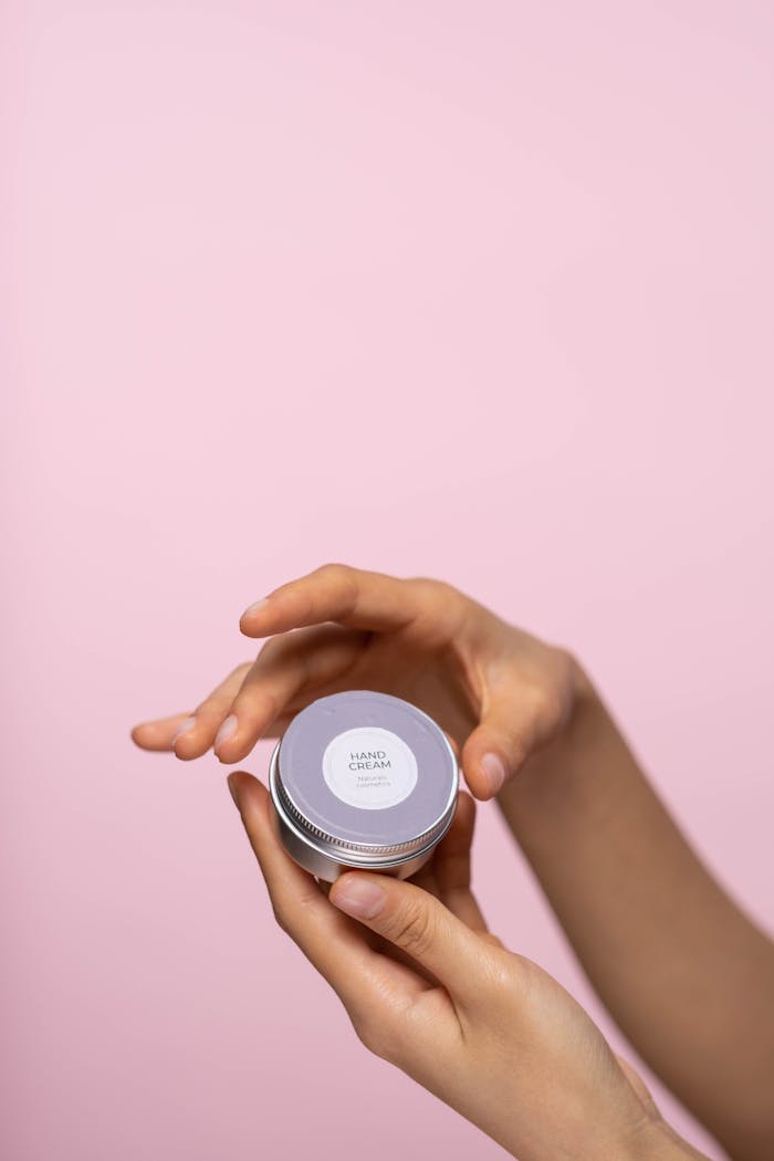 Crafting Captivating Headlines: Your awesome post title goes here Elegant hand cream jar held by hands against a soft pink background, showcasing skincare simplicity.
